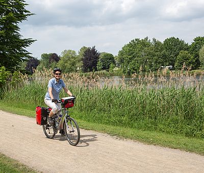 Frau radelt an der Ems entlang